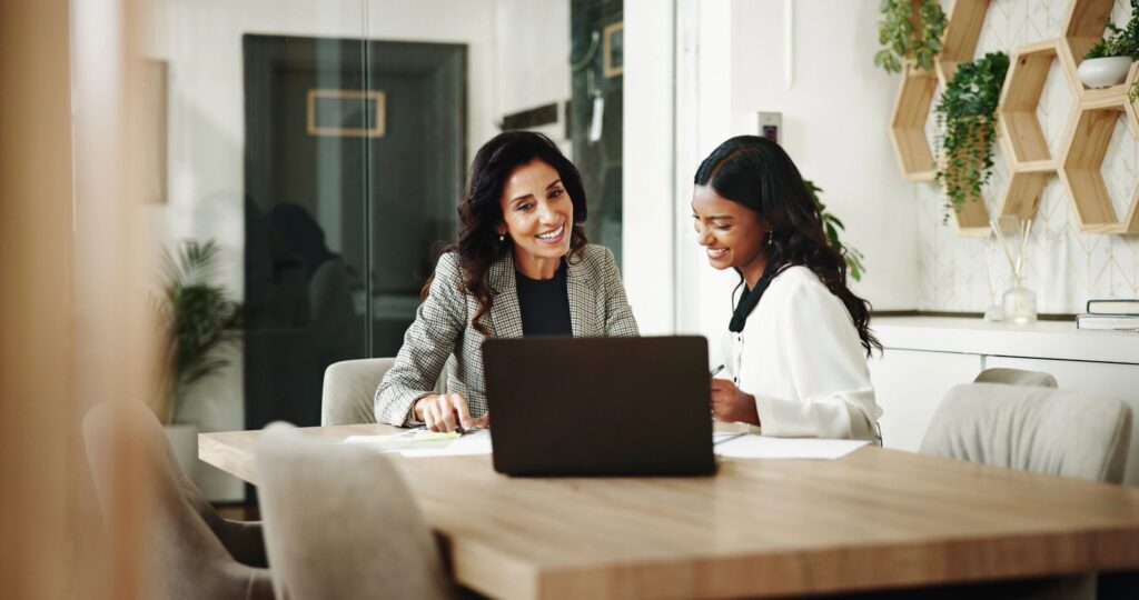 Two women collaborating on a laptop in a cozy office setting.