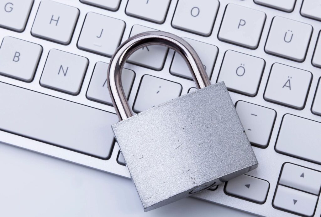 A silver padlock resting on a white keyboard symbolizing security.